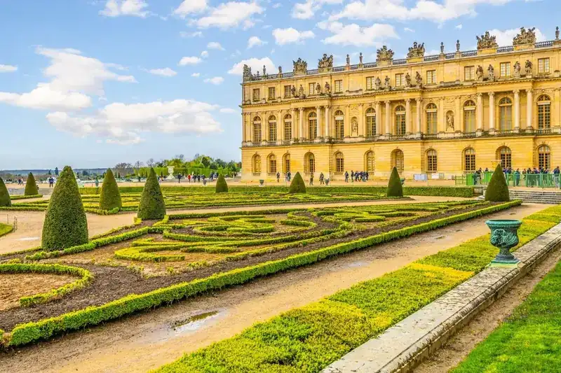 Broderie parterre hedges and topiary cones beside the Versailles palace garden facade in spring